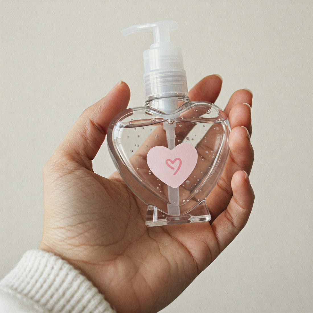 hand holding a heart-shaped bottle of hand sanitizer